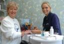 St Christopher's Hospice representative Thirza Channell gets given a beauty treatment by Louisa Walsh