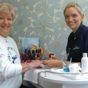St Christopher's Hospice representative Thirza Channell gets given a beauty treatment by Louisa Walsh