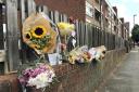 Floral tributes left on a fence near to the scene in Adolphus Street. Henry Vaughan/PA Wire