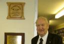 Mr Ellerby beside the plaque commemorating the opening of the school.