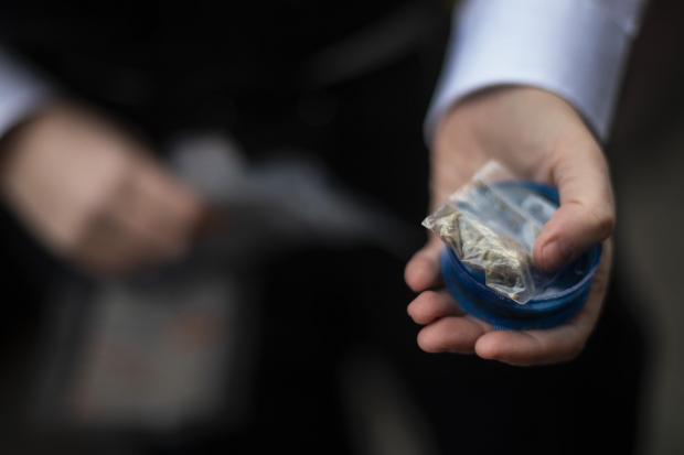 News Shopper: A female police officers holds a small bag of suspected cannabis found during a stop and search of a suspect in London Bridge (PA)