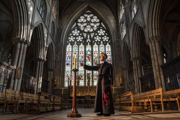 News Shopper: Very Reverend John Dobson Dean of Ripon lights a candle to mark the second anniversary of the first national coronavirus lockdown at Ripon Cathedral, North Yorkshire, ahead of the National Day of Reflection on Wednesday (PA)