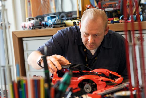 News Shopper: A man assembling the LEGO Technic Ferrari Daytona SP3. Credit: LEGO