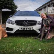 Justin Scrutton, who runs Justin Time Travel in Dartford, pictured with his car, number plate and dogs