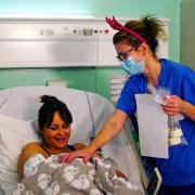 A medical staff member wearing a pair of festive antlers talking with a mother and her newborn baby on the labour ward at King's College Hospital in south east London