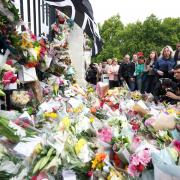 People look at flowers laid outside Buckingham Palace, London, following the death of Queen Elizabeth II on Thursday
